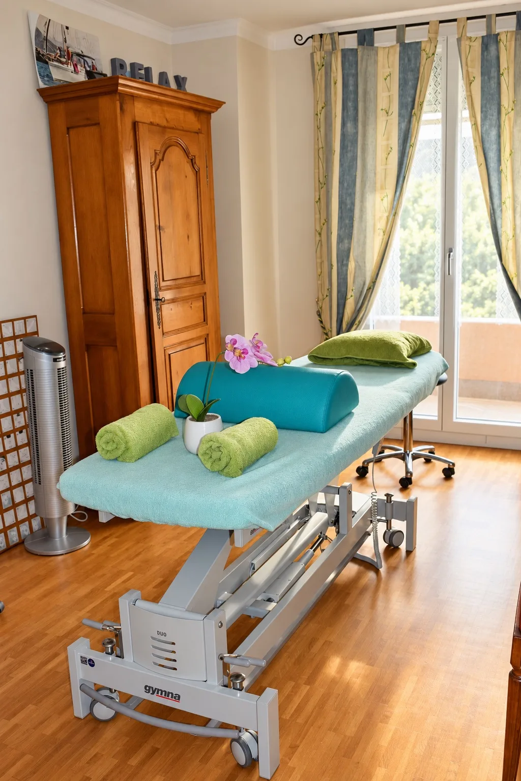 Salle de soin du cabinet Au Koala Zen à Penthalaz : table de soin, serviettes roulées et orchidée, lumière naturelle