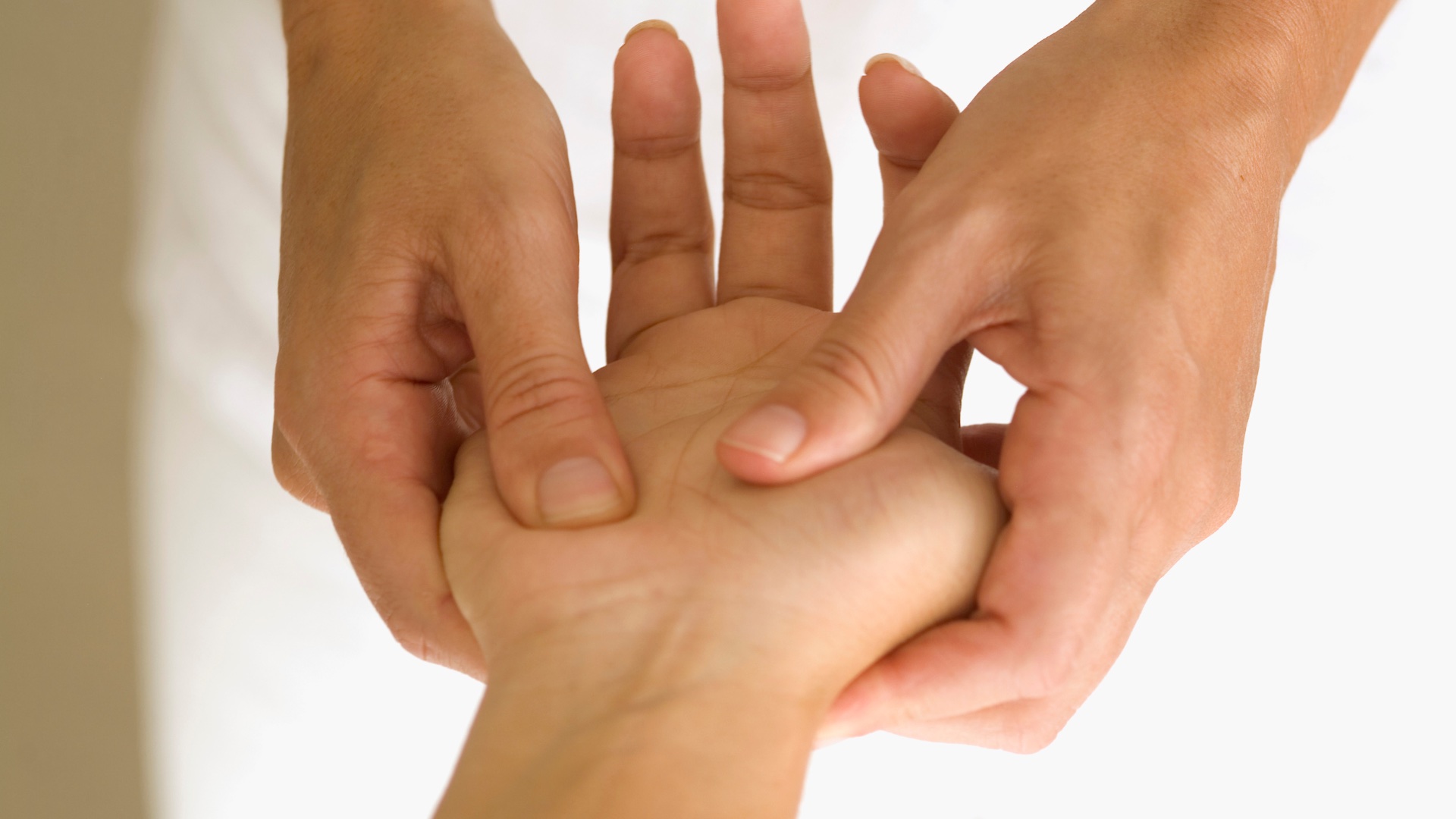 Pression des pouces dans la paume, pendant une séance d’acupressure.
