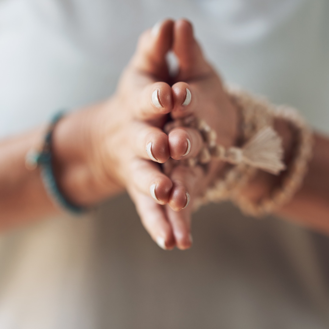 Mains jointes devant le buste, bracelets de perles, geste de recentrage