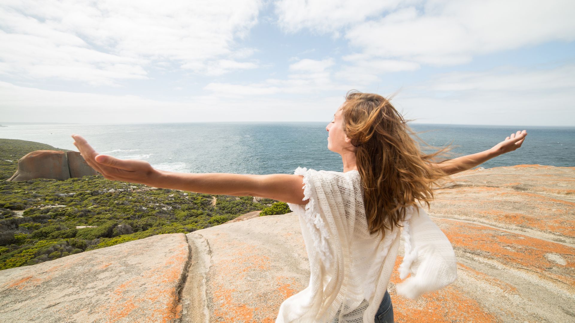 Femme bras ouverts face à la mer, sensation d’allègement